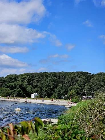 En strand vid kusten med sand, hav och en vik, perfekt för rekreation och semester.