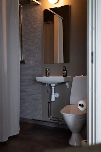 Ett modernt och rent badrum på Skuleberget Havscamping med ljusa väggar, toalett, handfat och klinkergolv.