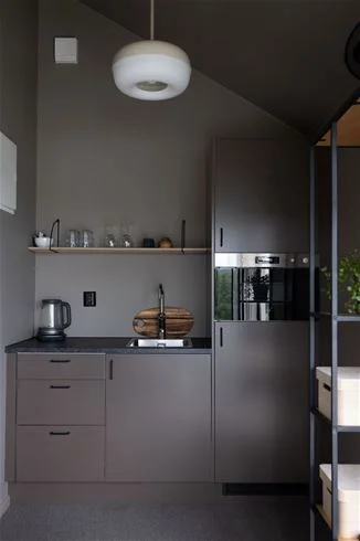 Alt-text: Interiör av en campingstuga på Skuleberget Havscamping med ljus träinredning, modernt kök, matplats och mysig belysning.