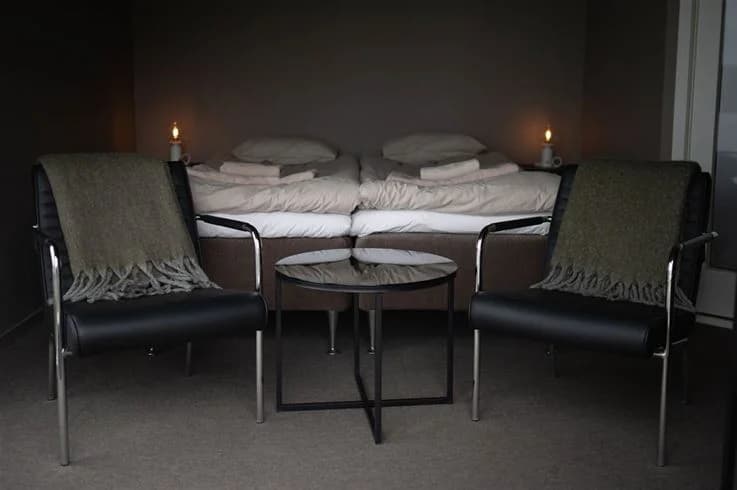 En väl upplyst campingplatsinredning med träpanel och moderna möbler, inklusive en bekvämgrå stol på ett trägolv.