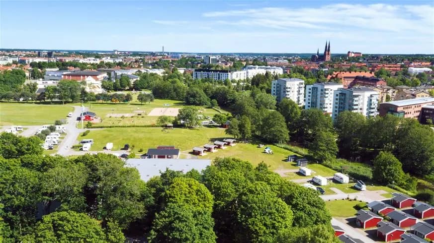 Flygbild som visar Fyrishov stugby och camping, omgiven av träd och bostadsområden i ett stadslandskap.