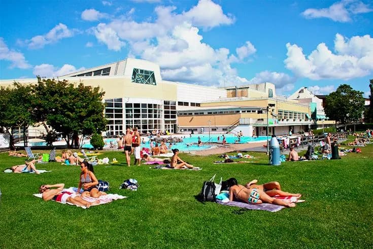 Bild av Fyrishov stugby och camping som visar ett rekreationsområde med en swimmingpool. Människor i badkläder njuter av semester och fritid i en avslappnad atmosfär. Resorten erbjuder en somrig och inbjudande miljö för besökare.