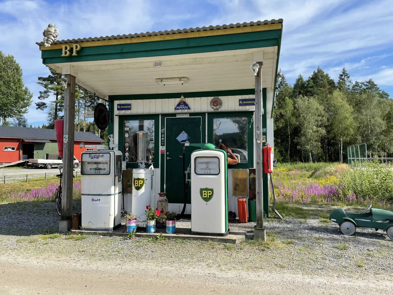 En bensinstation med bränslepumpar och slangar, omgiven av grönska nära Bullarebygdens familjecamping.