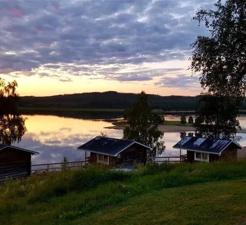 En rofylld sjö vid Särna Camping i kvällsljus, med spegelblanka vatten och en skogskantad strandlinje.