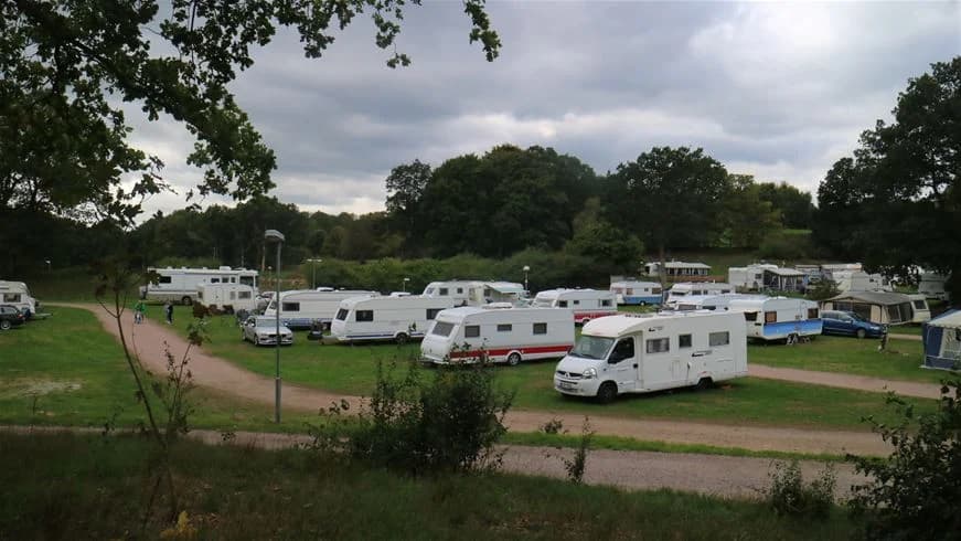 Bild av Grottbyns Camping som visar en trädbevuxen landskap med husbilar och husvagnar parkerade. Området är en blandning av natur och campande fordon, med grönska som skapar en lugn och avkopplande atmosfär.