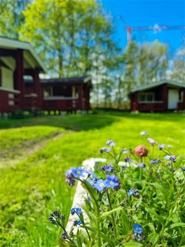 En grönskande campingplats med gräs, buskar och småstugor i en lantlig miljö i Trollhättan.