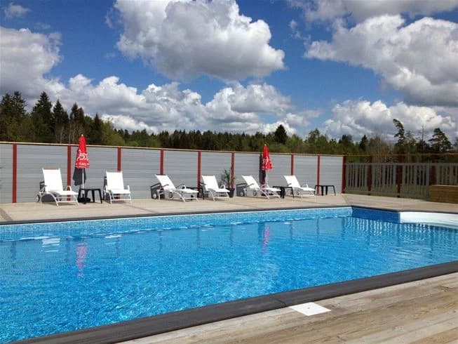 Alt-text: "En inbjudande campingplats vid Stenrösets camping i Trollhättan med en swimmingpool omgiven av utomhusmöbler, perfekt för avkoppling och njutning."