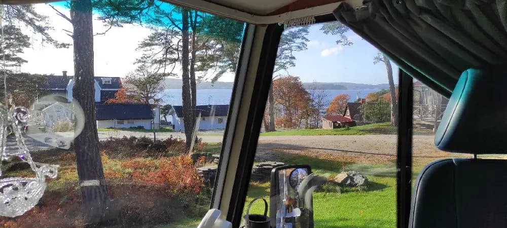 En solig dag på Stenungsögården, med utsikt från en bil som visar solskyddade glasrutor och ljus som strilar genom trädtopparna.