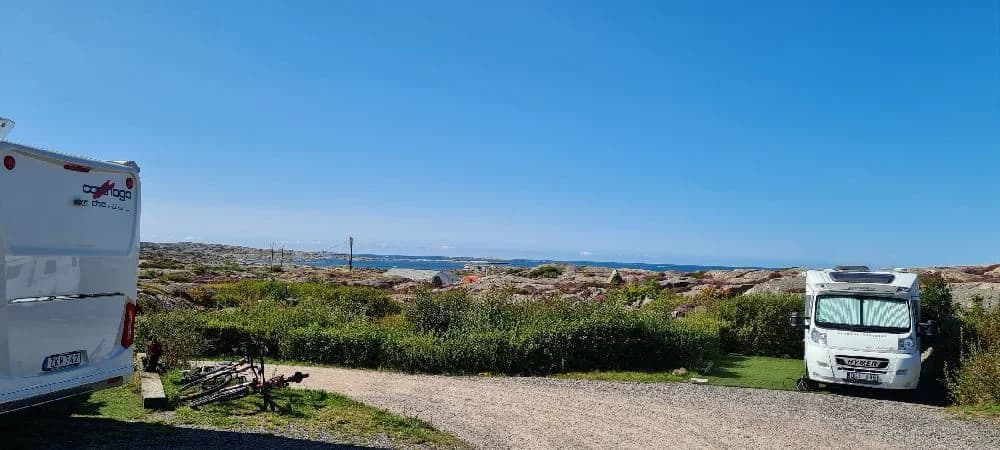 En campingplats med uppställda husbilar och husvagnar i Sotenäs, omgivna av grönska.