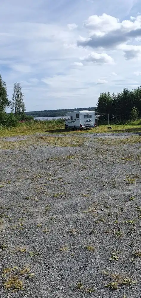 En vidsträckt landskapsvy över Trångsvikens bygdegård med öppna fält under en molnig himmel.