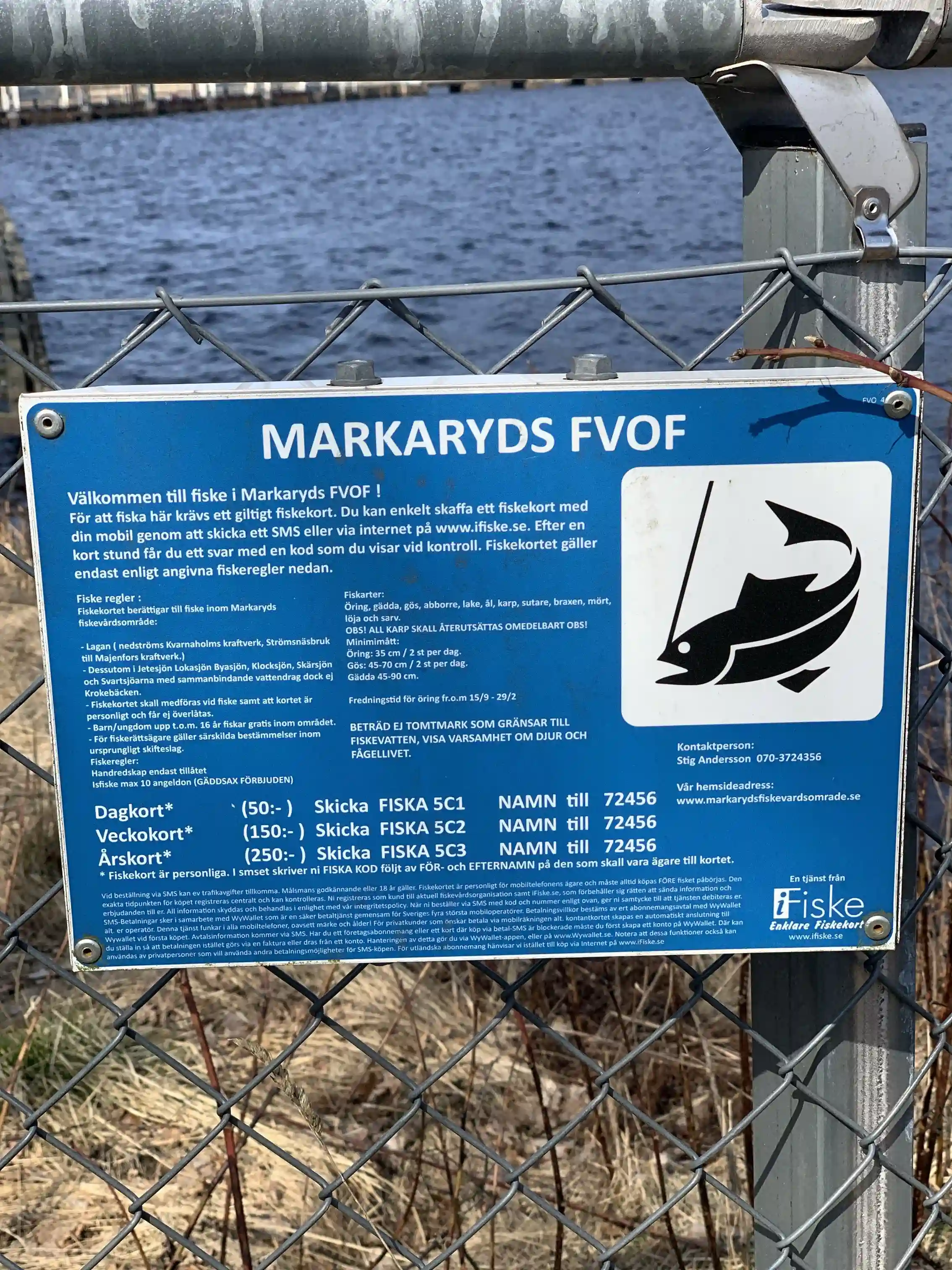 En skulptur av en sovande älg gjord av metallnät, placerad utomhus i en naturlig omgivning med grönska i bakgrunden.