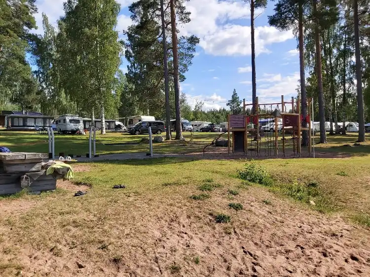 En grönskande campingplats med utspridda träd och gräsmattor, omgiven av öppna ytor och parker, vid Tällbergs camping.