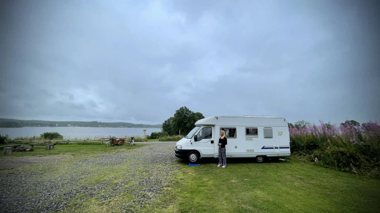 En husbil och en husvagn parkerade på Säms Camping, omgivna av en vacker våtmarksmiljö.