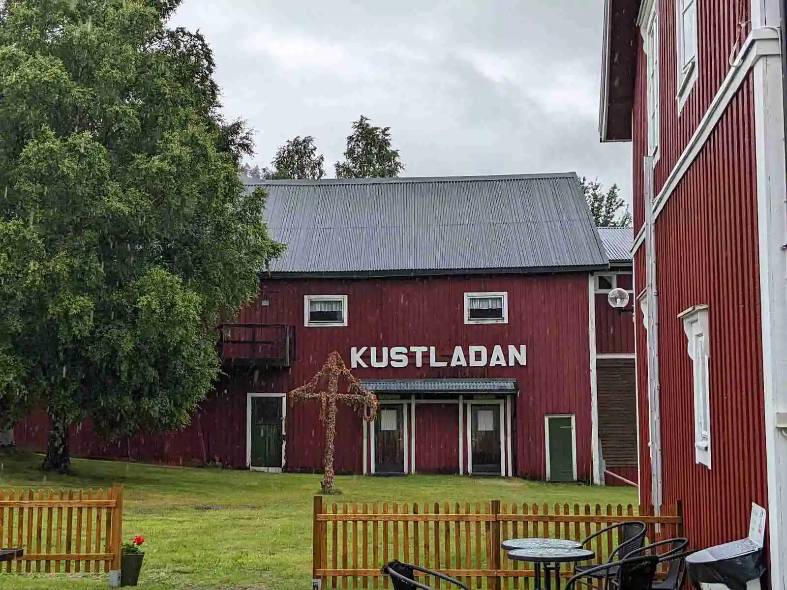 En bild av Docksta Vandrarhem & Camping Kustladan, som visar byggnadens fasad med omgivande grönska och klar himmel ovan. Ett lugnt och inbjudande boende beläget på landsbygden.