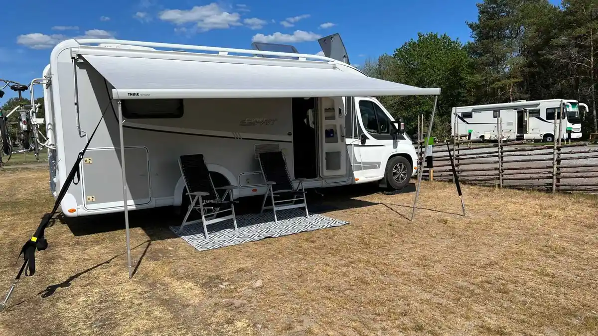 Bild av en ställplats och camping i Broakulla med flera husbilar och husvagnar parkerade på grusunderlag, omgivna av grönska.