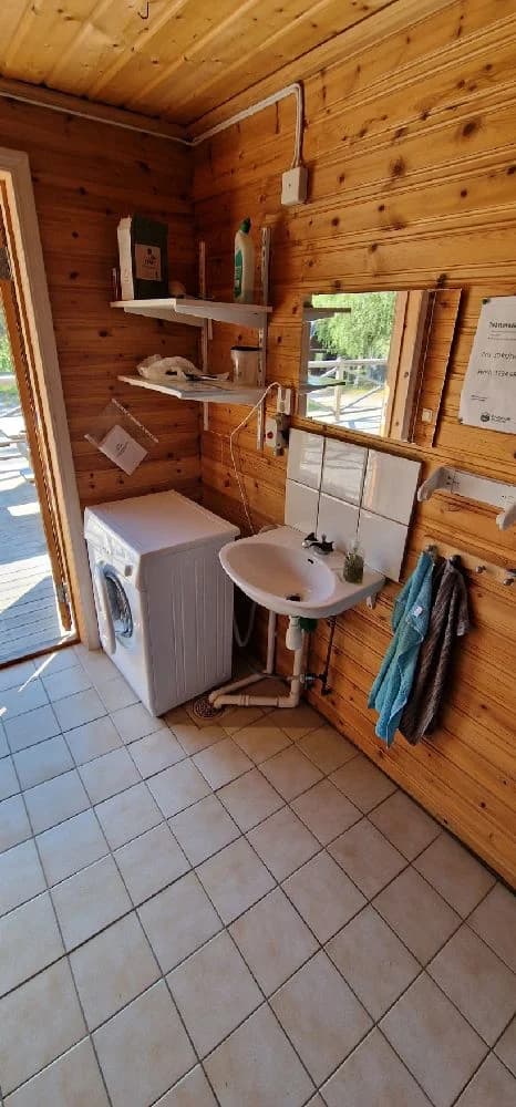 En mysig interiör av en timmerstuga med trägolv, träpanelade väggar och en dörr i bakgrunden, typisk för Bjurholms Camping.