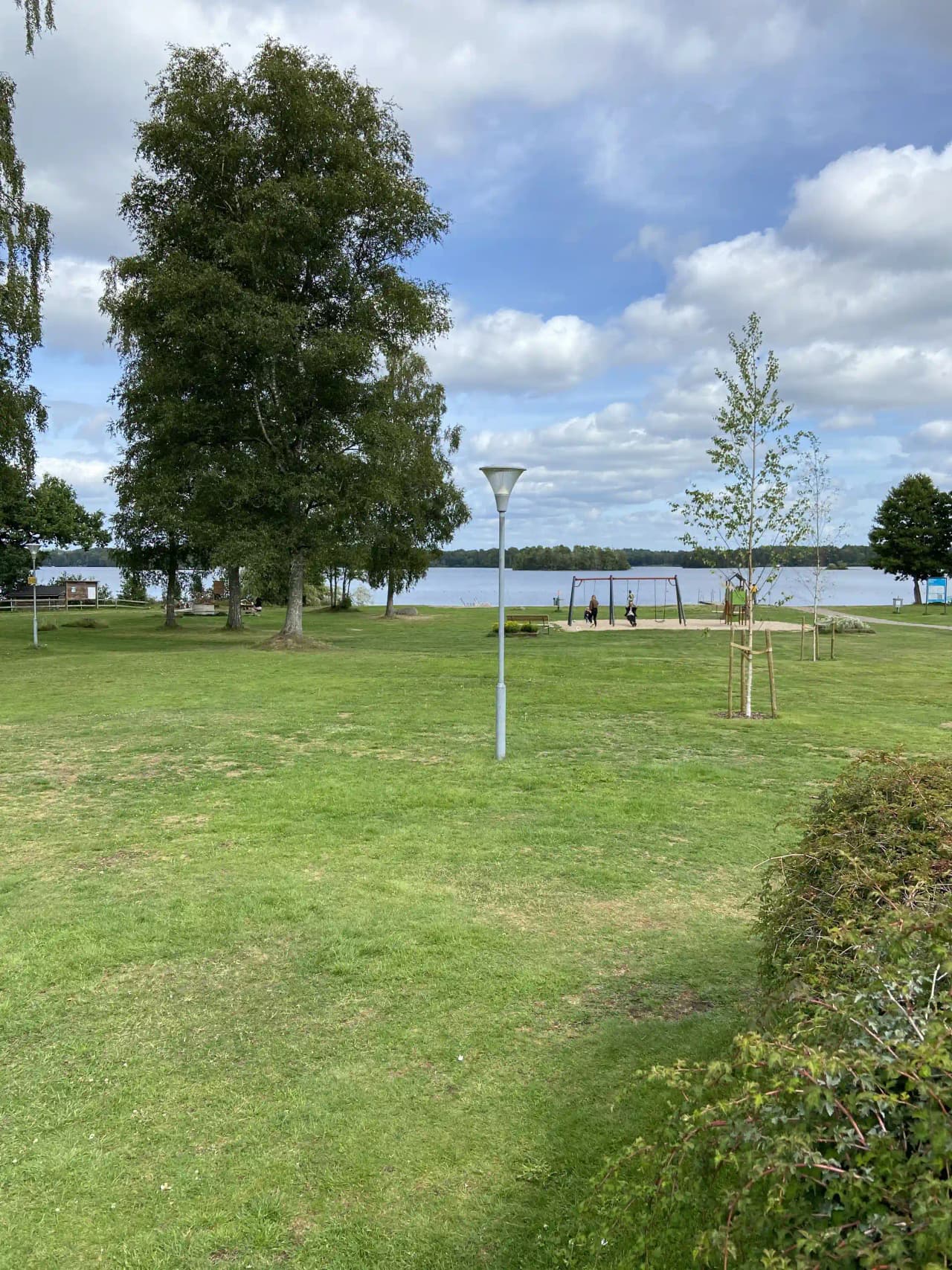 En somrig vy över Öjaby camping med grönskande gräsmatta och omgivande växtlighet i en lugn och naturlig miljö.