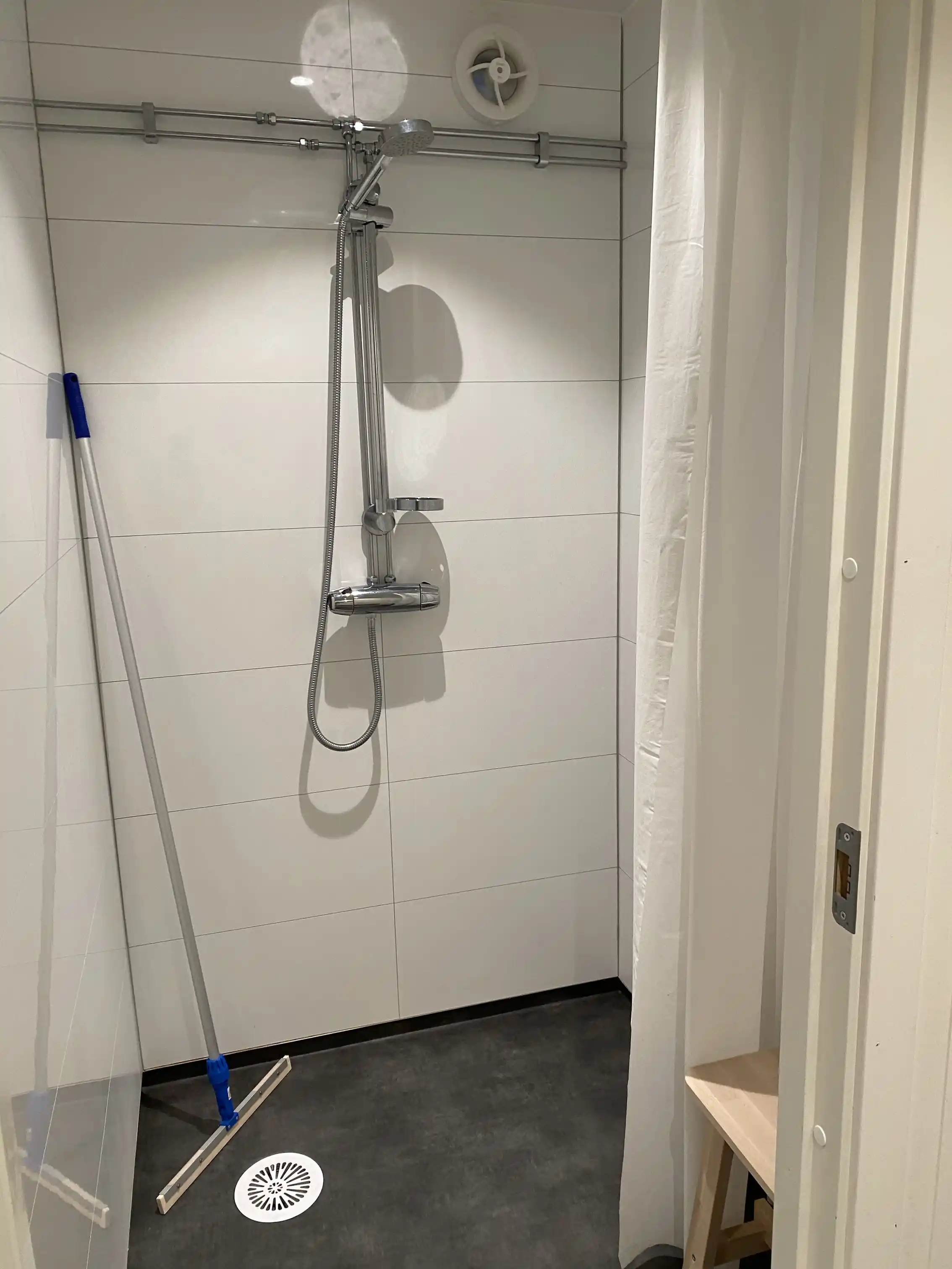 Bild på ett helkaklat badrum med en modern dusch. Duschpanelen är utrustad med flera munstycken och en duschstång. Klinkergolv matchar de stilrena väggplattorna.