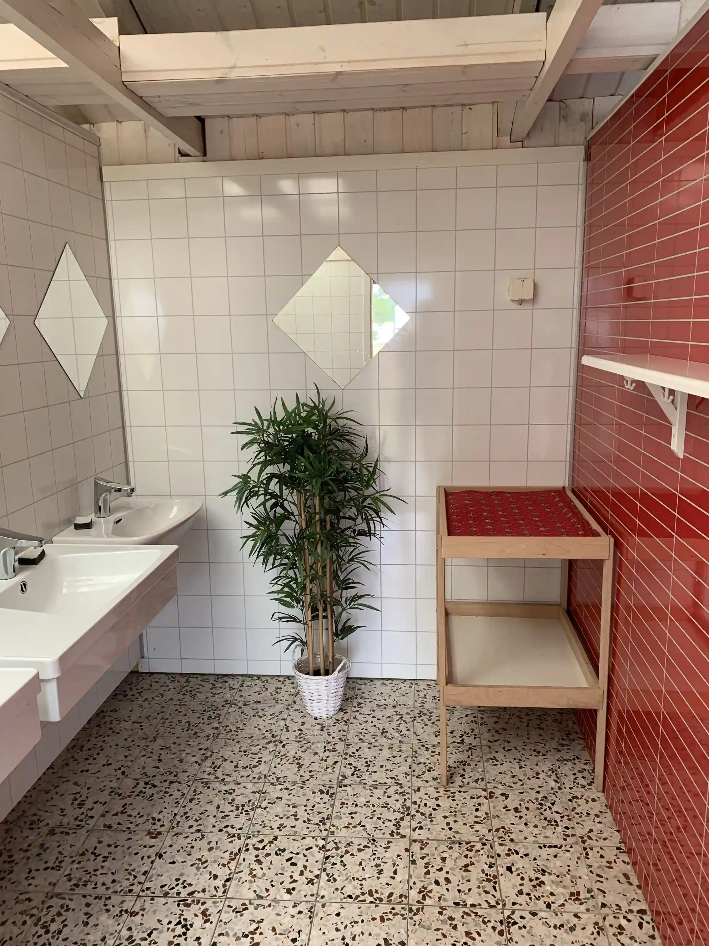 Ett interiörfoto från Gudingebadet visar ett kaklat golv och väggar, med sanitetsarmaturer synliga. Kakelplattor pryder golvet vilket ger ett rent och stilrent intryck.