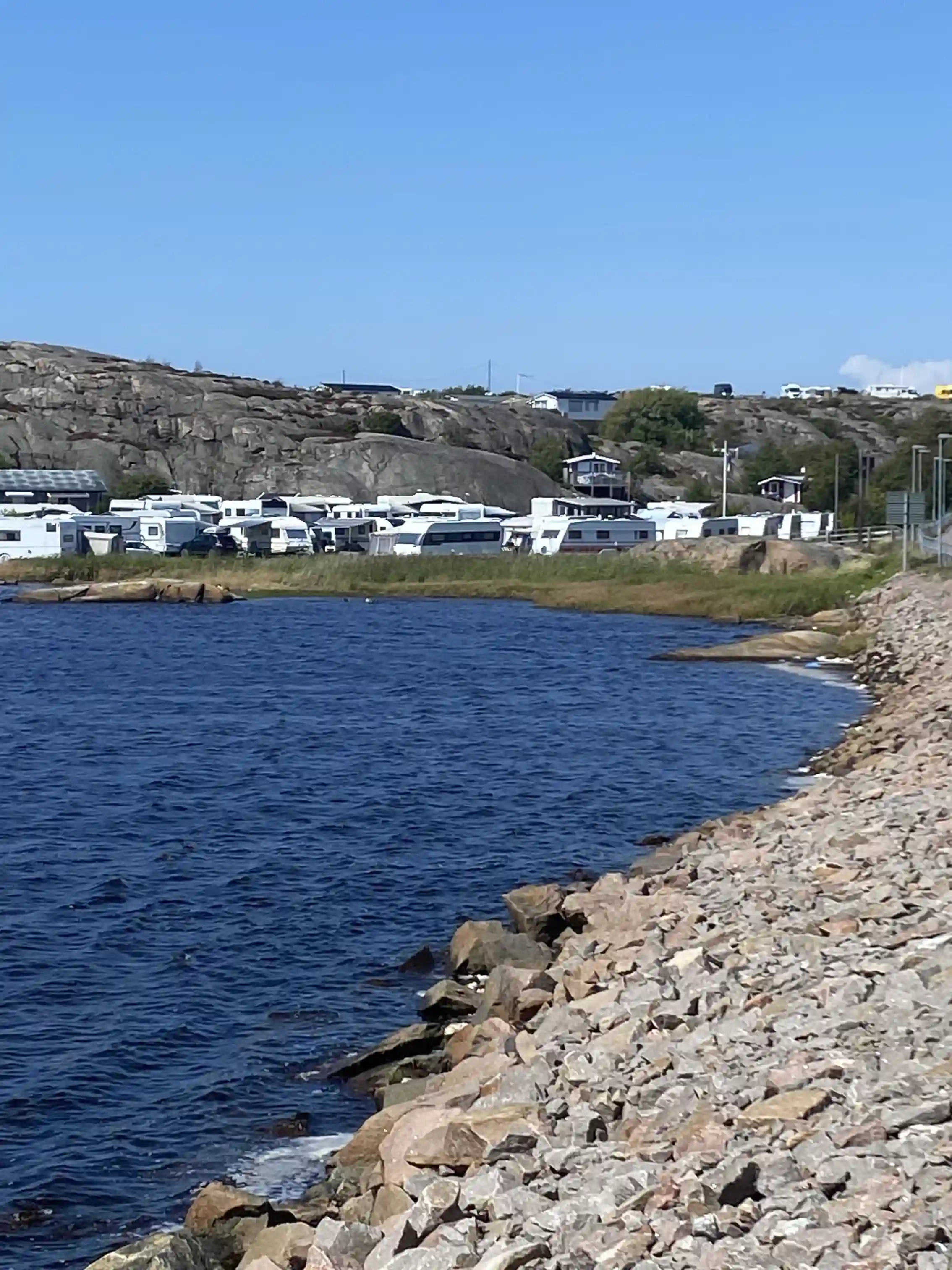 Vy över kustlinjen vid Sotenäs Camping med vattendrag och hav i bakgrunden, samt en sandstrand i förgrunden.