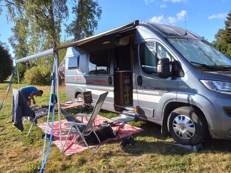 En husbil parkerad på en campingplats vid Farstanäs Camping & Havsbad, omgiven av cyklar och andra campingfordon.