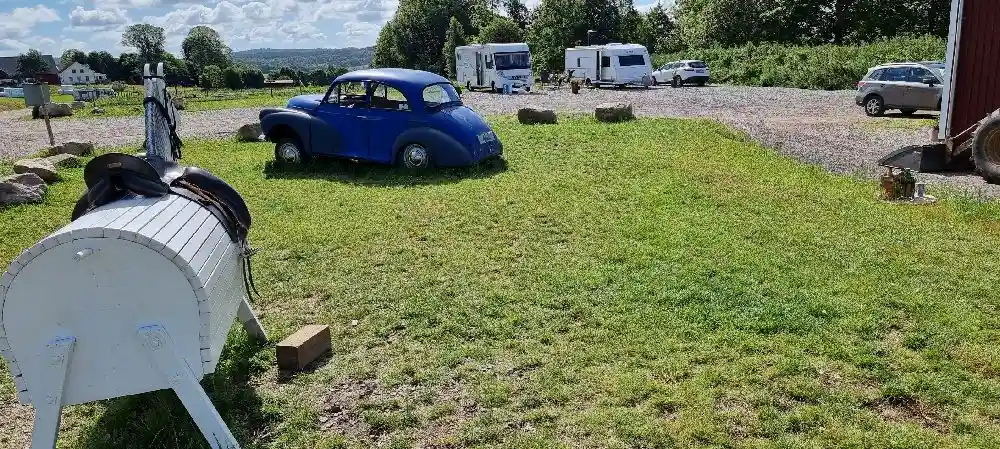 En klassisk bil står parkerad på en uppfart omgiven av en välskött gräsplätt och trädgård vid Gunnagård.