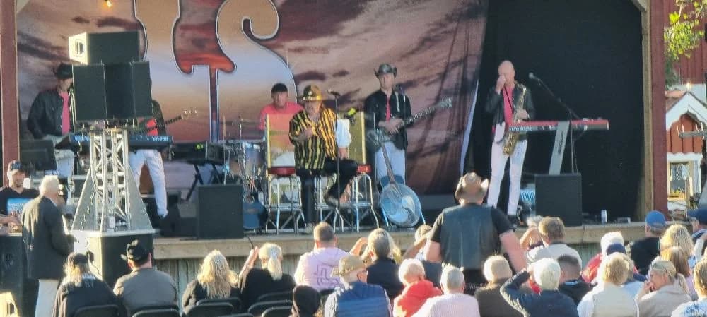 En musiker spelar gitarr på en scen under ett framträdande på Gunnagård.