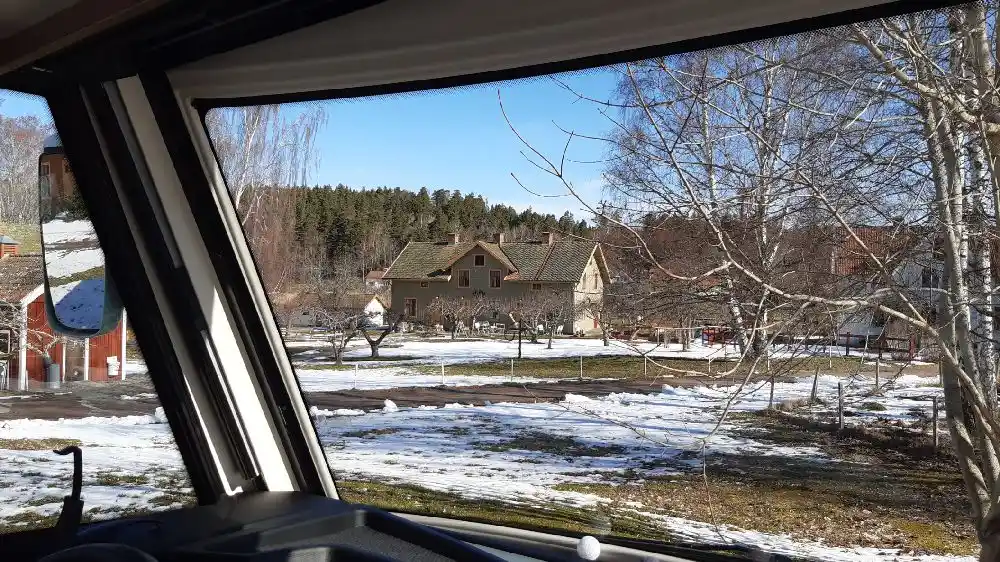 En vintrig scen vid glasbruket, med snötäckta grenar och glasdetaljer som reflekterar dagsljuset.