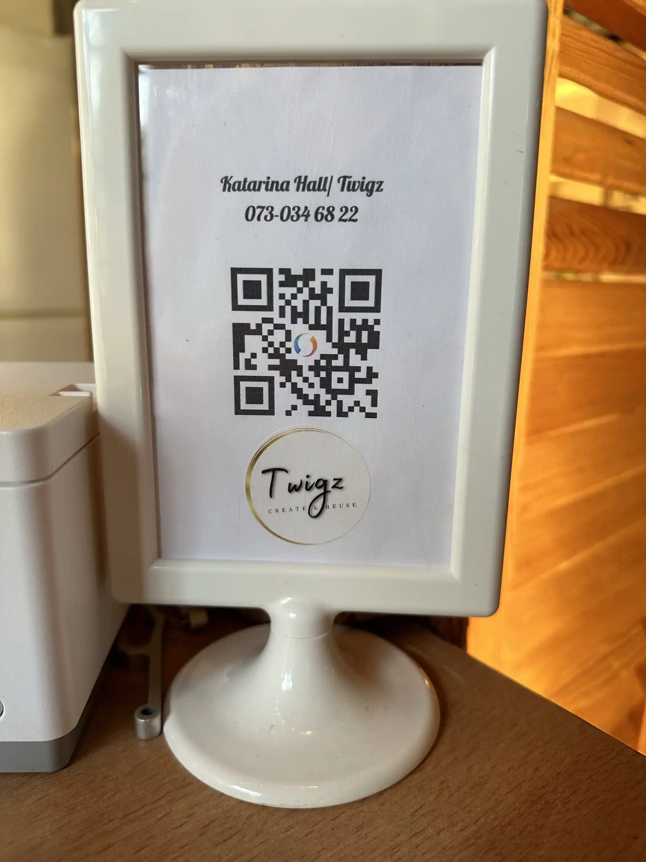 En vit, traditionellt designad byggnad med röda detaljer, omgiven av grönska och en grusväg, typiskt för en svensk bygdegård.