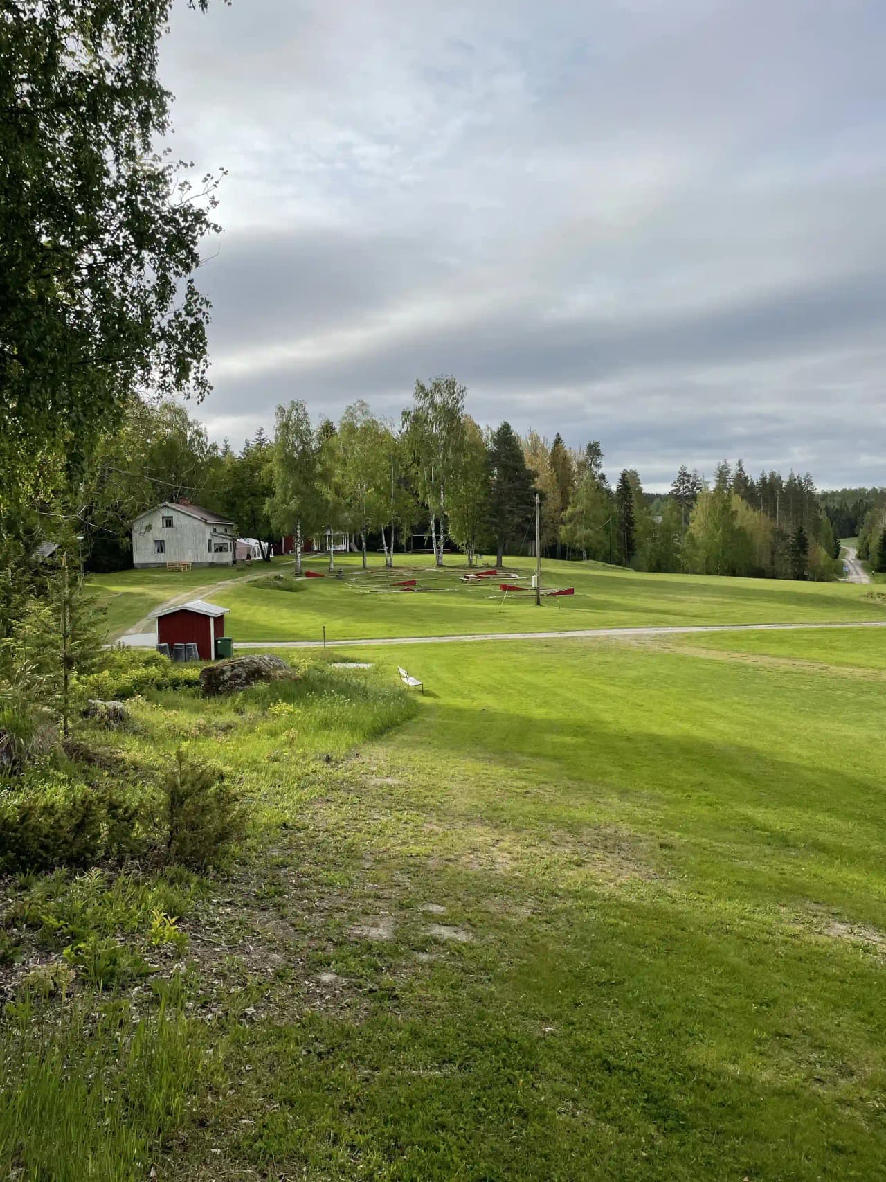 En grönskande campingplats vid Valasjön med vidsträckt gräsmatta, omgivande träd och öppen naturlig miljö.