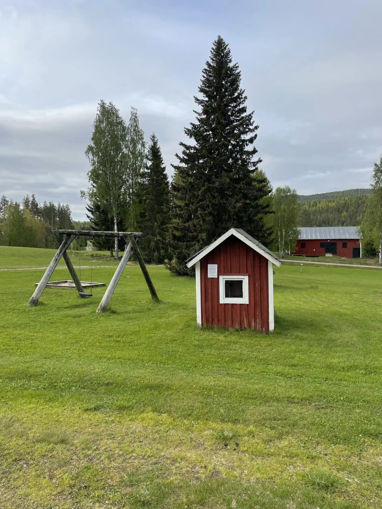 Bild av Valasjöns camping som visar en gräsbevuxen campingplats med en enkel stuga, omgiven av en äng och öppna ytor.