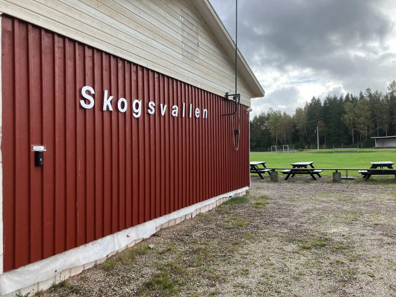 En närbild på en träfasad vid besöksmålet Skogsvallen i Ale, med tydliga träpaneler i naturliga jordtoner som utgör byggnadens sidoklädsel.