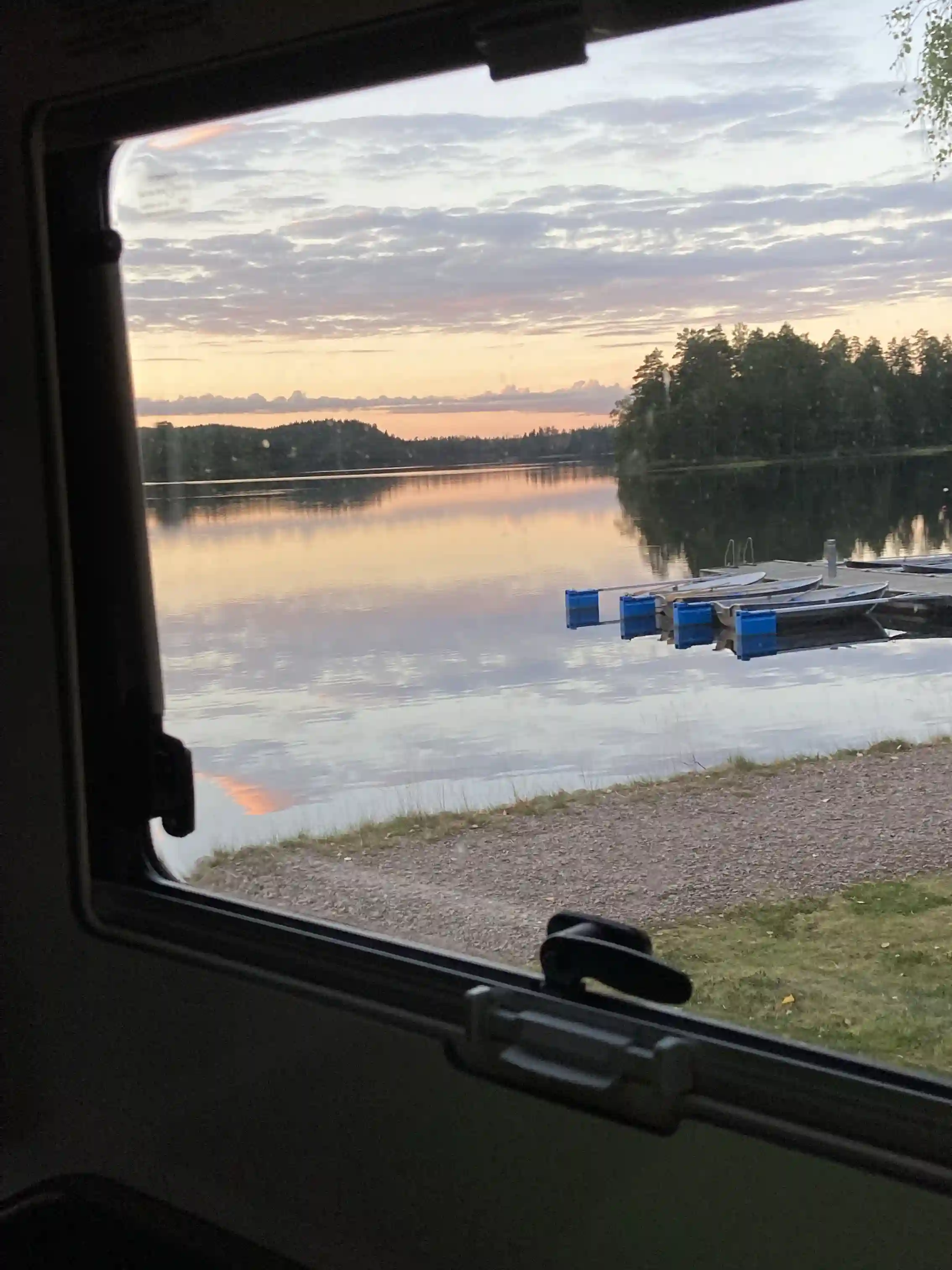 En vacker sjö vid skymning med spegelblankt vatten som reflekterar kvällens mjuka ljus, omgiven av naturlandskap.