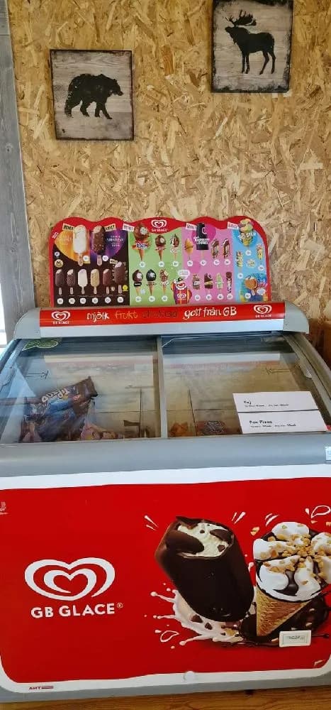 En skylt vid Hamra Stugby som annonserar om glass och desserter, med fokus på lockande bilder av glass och frysta desserter.