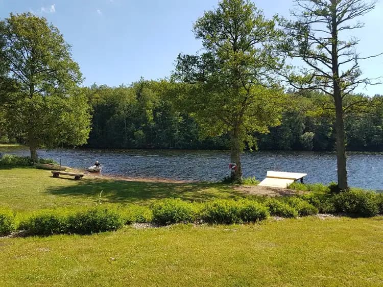 Ljuvadal Camping & Ställplats: En rofylld campingplats med grön natur, vid en kropp av vatten omgiven av träd och gräsyta.