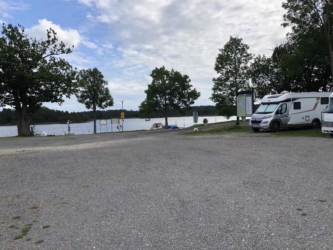 En parkeringsplats vid Upperuds Gästhamn, omgiven av natursköna sjölandskap.