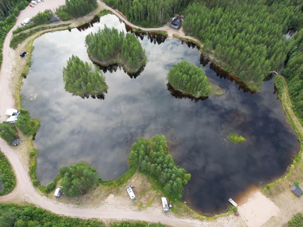 Flygfoto över en naturskön sjö med omgivande våtmarker och skogar i Mora, som erbjuder möjligheter till vildmarksfiske.