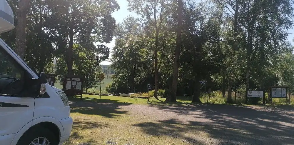 Bild av en parkeringsplats på Badsta Camping med flera typer av fordon, inklusive bilar, skåpbilar och husvagnar, vilket indikerar en populär plats för besökare med olika transportmedel.