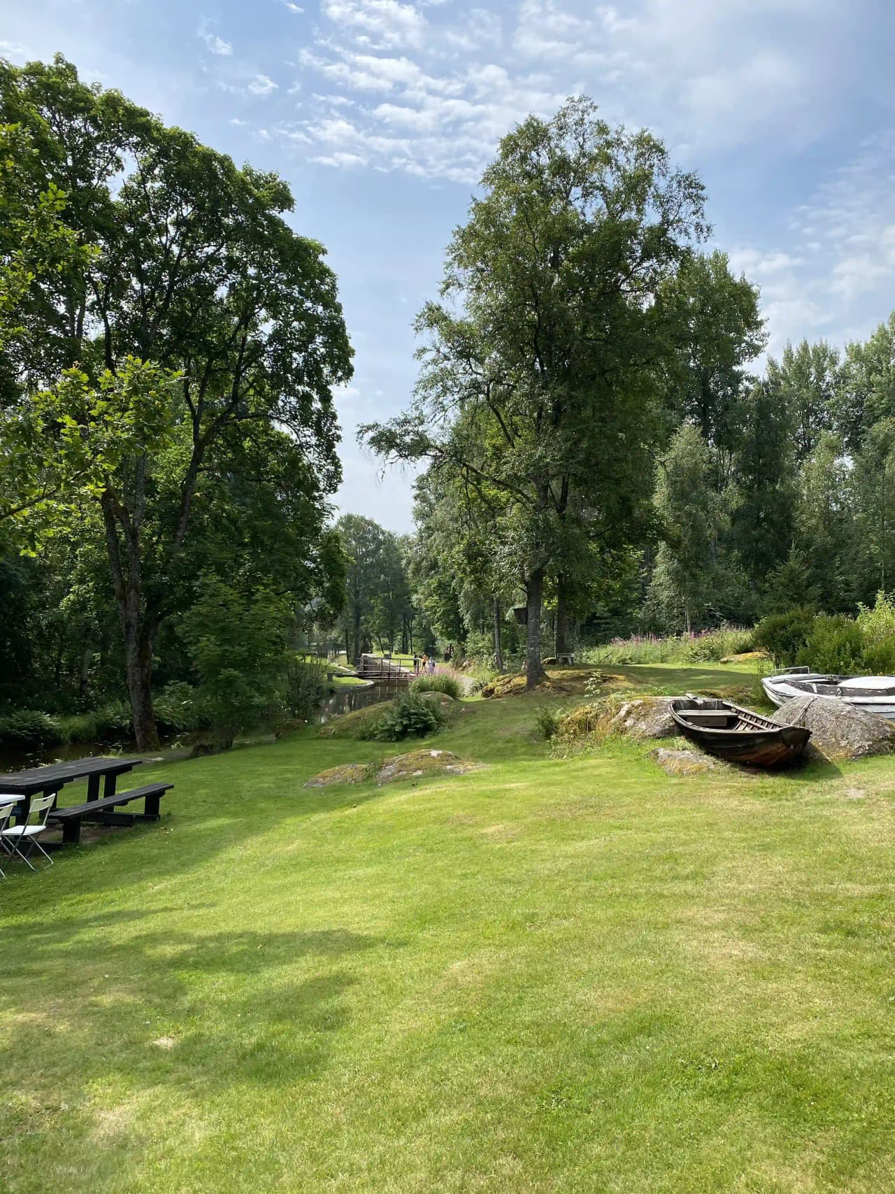 En grönskande camping med träd och gräsmarker omgiven av buskar och trädgrenar.