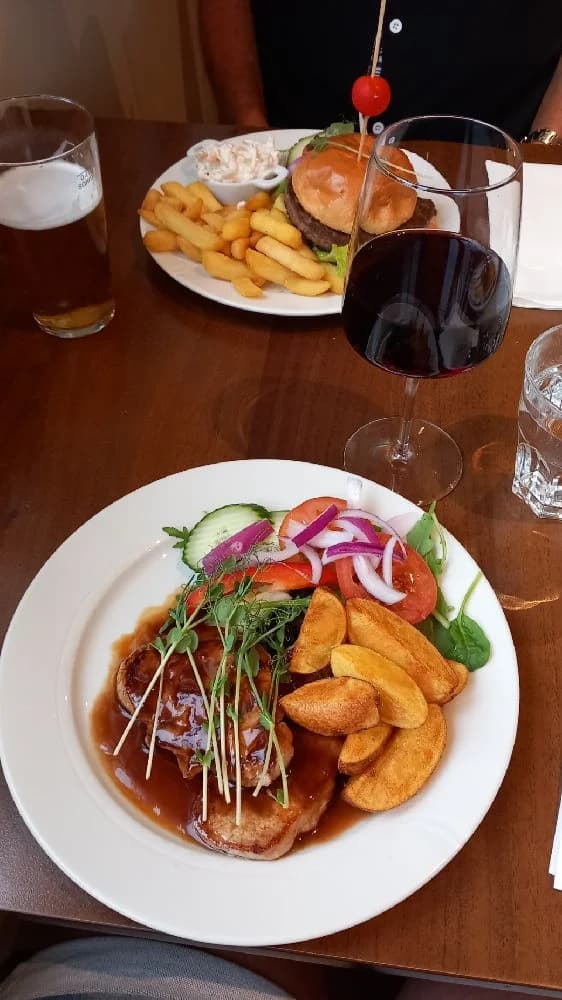 En campingplats med ett dukat bord utomhus, där mat och dryck är uppsatt för servering. Bordet har tallrikar, glas och stekta maträtter som skapar en inbjudande och avslappnad atmosfär.