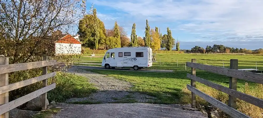 En husbil parkerad på Kedumsvik ställplats, omgiven av grönska och en välordnad parkmiljö.