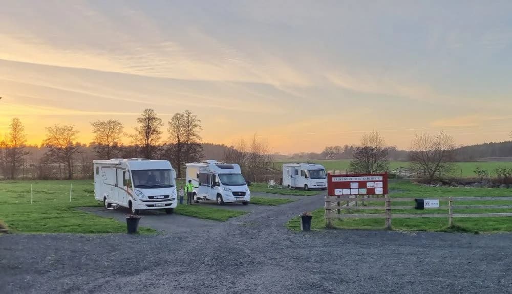 En ställplats vid Kedumsvik med flera parkerade husbilar och husvagnar på en grusparkering.