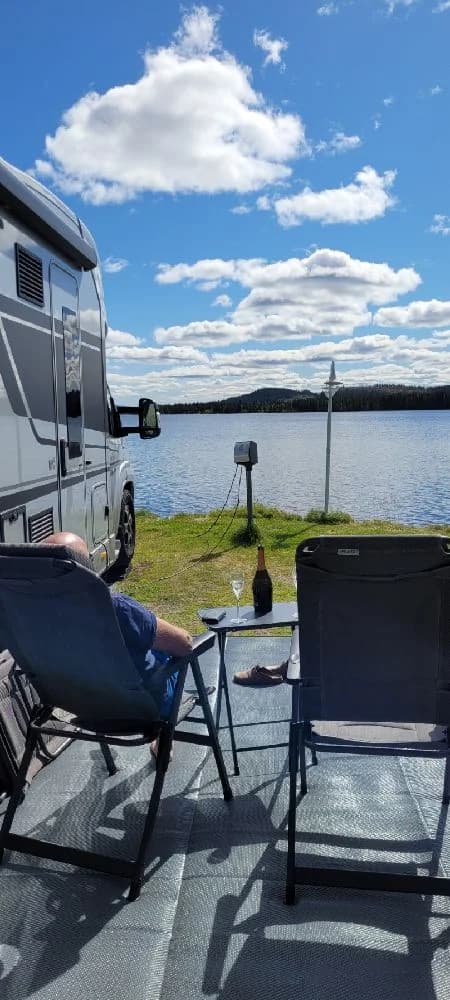 En uteplats med solstolar och bord i trä, omgiven av natur, på Kolgårdens stugby & camping. Perfekt för rekreation och avkoppling.