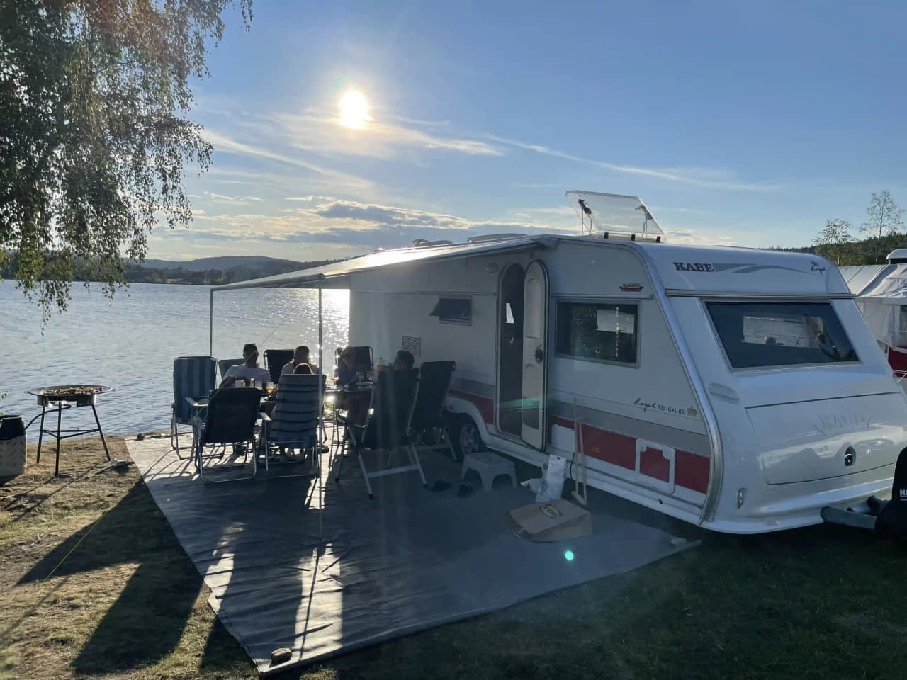 En husvagn och husbil parkerade på Snibbens campingplats, omgivna av grönska och campingutrustning.