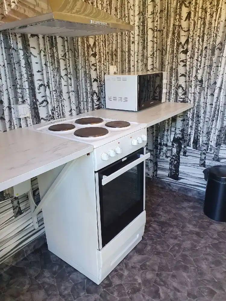 Ett kök med moderna vitvaror, inklusive en gas- eller elektrisk spis och köksskåp. Rummet är en del av bekvämligheterna på Snibbens Camping och ger en hemtrevlig känsla för besökare.