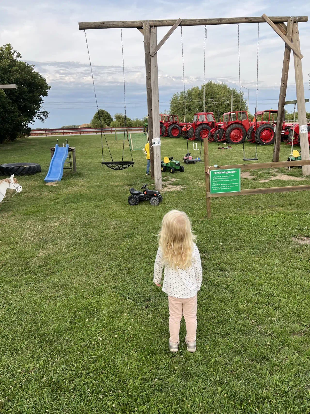 Bild av en grönskande rekreationsplats vid Gripenbergs gård, med lekutrustning och lekande barn på en gräsmatta under en klar himmel. Perfekt för familjeutflykter och fritidsaktiviteter.