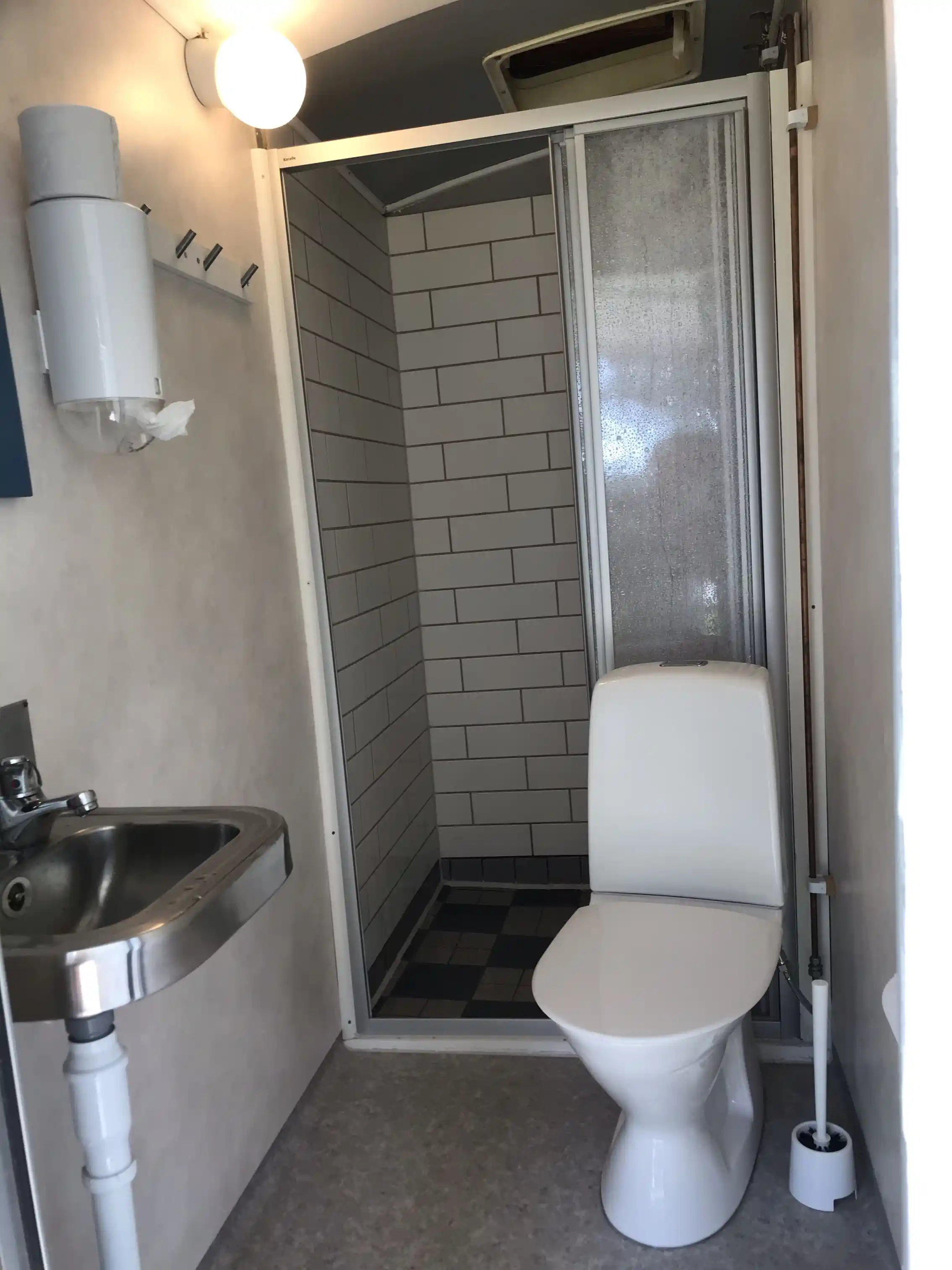 Bild på ett badrum på Furudals vandrarhem och sjöcamping med ett vitt handfat och en toalett på ett kaklat golv.