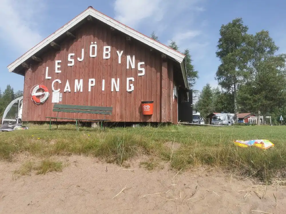 En campingplats med uppställda tält i en naturskön miljö med gröna träd och ett parklandskap, Lesjöbyns camping erbjuder friluftsliv och avkoppling.
