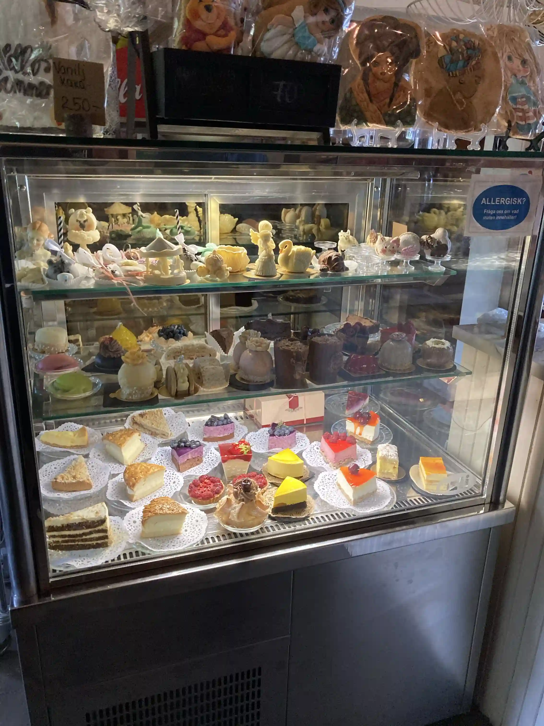 En bild som visar en display med bakverk och desserter på Lesjöbyns camping. Det finns tårtor och andra bakverk fint uppställda på hyllor i ett kaféliknande utrymme.