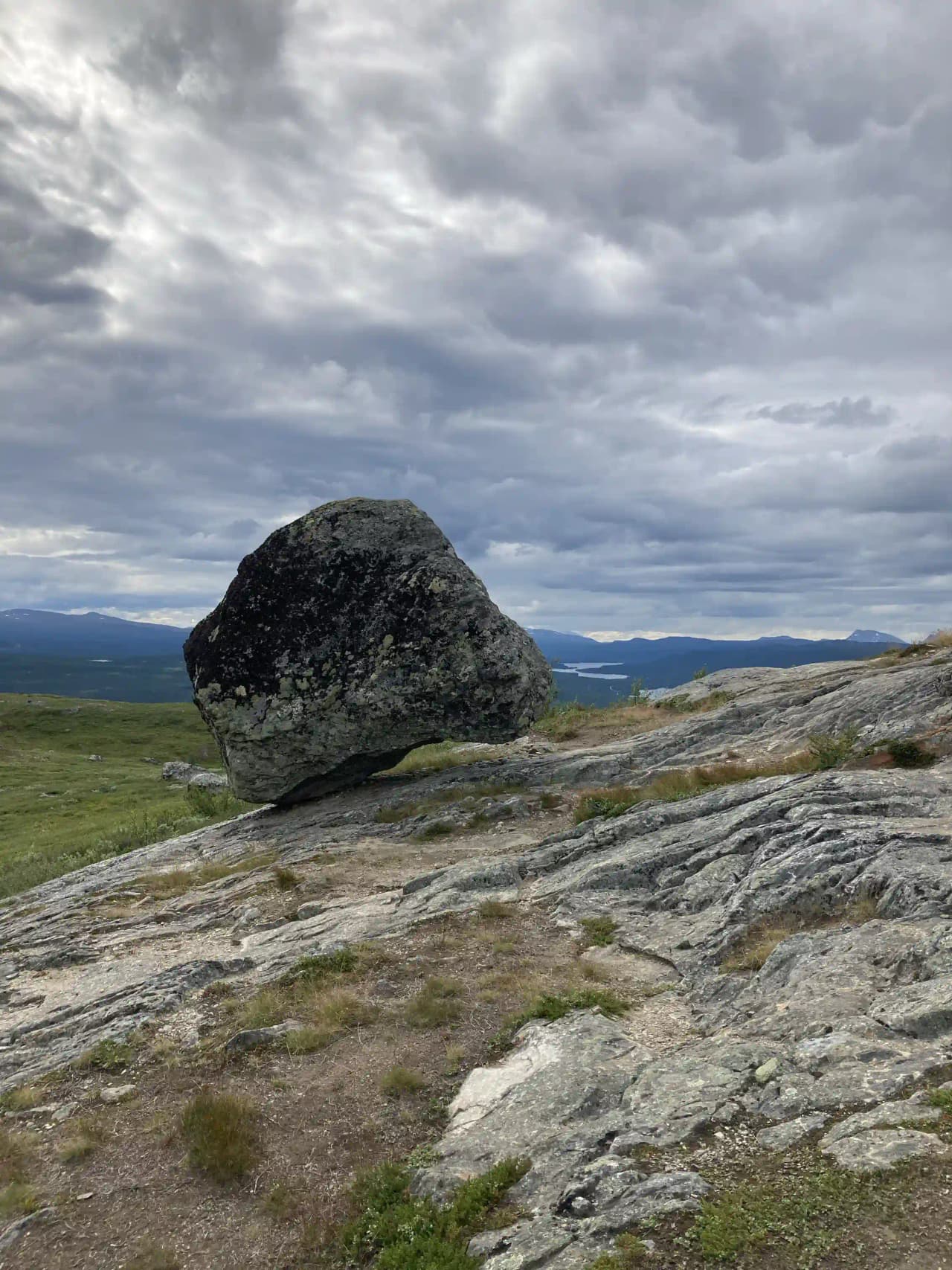 En naturskön utsikt över berg och grässlätter i Tärnaby, med dramatiska bergsformationer under en molnig himmel.